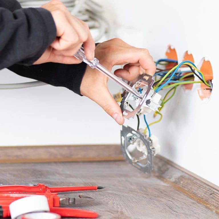 Artisan SOSRENO raccordant un interrupteur